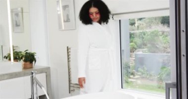 Ev banyosuna girmek, kadının krom musluğa dönmesi, sıcaklığı test ederken küveti doldurması. Lüks, rahatlama, dinginlik, çağdaşlık, refah, minimalizm, evcilik