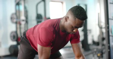 Dambılı gören, spor salonunda güç için kürek çeken Afro-Amerikan bir adam sonra da akıllı bakışları kontrol eden. Kuvvet, fitness, antrenman, atletik, kararlılık, motivasyon, egzersiz