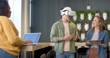 VR kulaklık takan, tablet ve dizüstü bilgisayarla incelemeyi takip eden çeşitli iş arkadaşları. Teknoloji, işbirliği, yenilik, dijital, modern, eğitim, daldırma