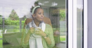 Afro-Amerikalı çift cam kapının önünde beklerken kadın kupayı yudumluyor ve gülümsüyor. Romantik, samimiyet, bağlantı, samimi, samimi, doğal, yaşam tarzı