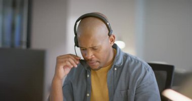 Destek çağrısını aldıktan sonra Afrikalı Amerikalı adam mikrofonu masaya indirip ekrandan konuşuyor. Teknoloji, iletişim, müşteri hizmetleri, profesyonel, modern, odaklanmış, uzak