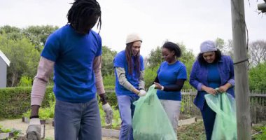 Toplum bahçesine vardıktan sonra çeşitli gönüllüler temizlik için ot topluyor. İşbirliği, takım çalışması, sürdürülebilirlik, açık hava, bahçıvanlık, birlik, çevre dostu