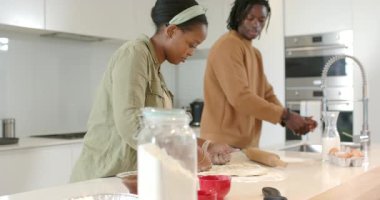 Afrika kökenli Amerikalı çift mutfak adasında yumurta kırıyor, ellerini yıkıyor ve hamurlarını yuvarlıyor. Yemek pişirme, takım çalışması, modern, aşçılık, yaşam tarzı, sağlıklı, yerli