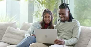 Çeşitli çiftler koltuğa telefon yerleştiriyor, pist dinliyorlar ve dizüstü bilgisayar ekranını gösteriyorlar, gülüyorlar. Çift, işbirliği, teknoloji, rahatlama, modern, yaşam tarzı, iletişim