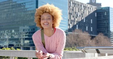Güneşli gökyüzü, Afrika kökenli Amerikalı bir kadını korkuluklara yaslıyor. Kahkahalarla gülüyorlar. Eğlence, eğlence, rahatlama, şehir, yaşam tarzı, hayat dolu, gülümseme.