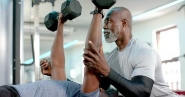 Afrika kökenli Amerikalı erkek müşteri spor salonunda ağırlık kaldırıyor. Eğitmen tutuşu güvenli bir şekilde ayarlıyor. Dayanıklılık eğitimi, spor, spor, spor, antrenman, antrenman, atlet, egzersiz