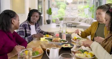 Çeşitli arkadaşlar karşılıklı gülümseme, salata servisi, modern yemek odasında tereyağı sürme. Yoldaşlık, sosyalleşme, konukseverlik, çağdaş, iç mekan, boş zaman, portre