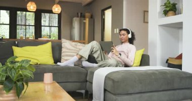 İçerik değiştikçe gülümseme kıvılcım saçar. İkili olmayan kişi oturma odasındaki kanepeye tablet atar. Modern, rahat, rahatlama, dijital, yaşam tarzı, ev, neşeli