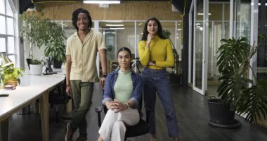 Kamera yakınlaştırması çeşitli iş arkadaşlarının gülümsemesine ve ofis çalışma istasyonunda takım güvenini göstermesine neden oluyor. İşbirliği, çeşitlilik, üretkenlik, modernlik, takım çalışması, profesyonel, ilham