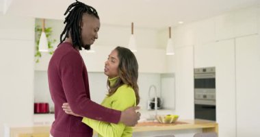 Çeşitli çiftlere sarıldıktan sonra mutfak adasının etrafında kolye ışıklarının altında meyve kasesiyle dönüyorlar. Romantizm, samimiyet, bağlantı, dans, sevgi, modern, sıcak