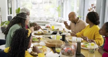 Büyükannem salata kasesini geçtikten sonra Afro-Amerikalı adam çatal kaldırdı ve yemek masasında sohbet etmeye başladı. Aile, toplanma, yemek, köy, canlı, birliktelik, kutlama