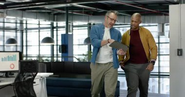 Veri talebinden sonra, çalışma masalarından geçen çeşitli erkek meslektaşlar tablet verileri gözden geçiriyorlar. İşbirliği, takım çalışması, dijital, modern, profesyonel, analitik, teknoloji