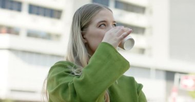 Kulaklık takan sarışın bir kadın elinde kahve fincanıyla plazaya giriyor ve bina perisine hayran kalıyor. Kentsel, gündelik, hayat tarzı, düşünceli, modern, dingin, enerjik.