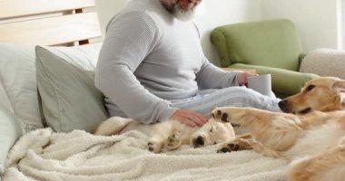 Uyanır uyanmaz, yetişkin beyaz bir adam elinde gri kupayla yetişkin bir köpeği selamlıyor. Samimiyet, dostluk, rahatlama, ev, kırsal, hassas, sıcak.