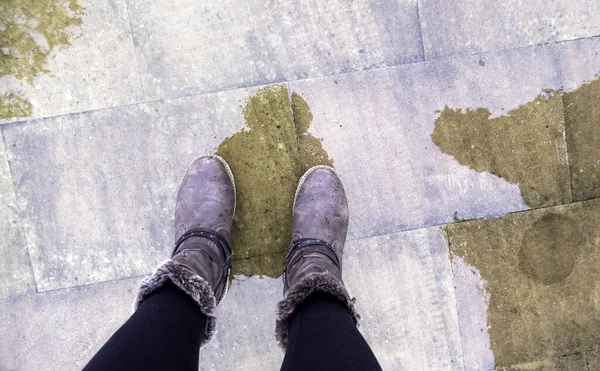 Detail of young woman with feet on a wet floor in the street