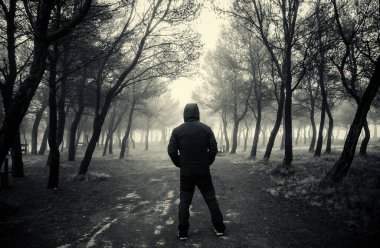 Karanlık ve ürkütücü bir ormanda yürüyen genç adamın ayrıntıları.