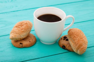 Cup of coffee with croissants on blue wooden table. Selective focus and top view