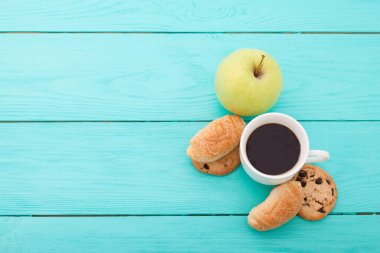 Cup of coffee with croissants on blue wooden table. Selective focus and top view