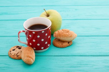 Cup of coffee with croissants and cookies and red roses on blue wooden background. Copy space. Mock up. Top view. Valentine mother day.
