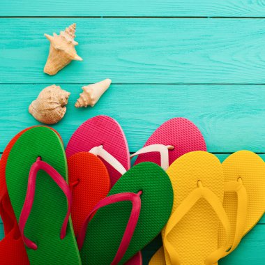 Yaz aksesuarları. Parmak arası terlik, güneş gözlüğü, havlu, kırmızı şapka ve portakallar mavi ahşap arka planda. Üst görünüm