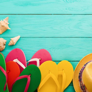 Yaz aksesuarları. Parmak arası terlik, güneş gözlüğü, havlu, kırmızı şapka ve portakallar mavi ahşap arka planda. Üst görünüm