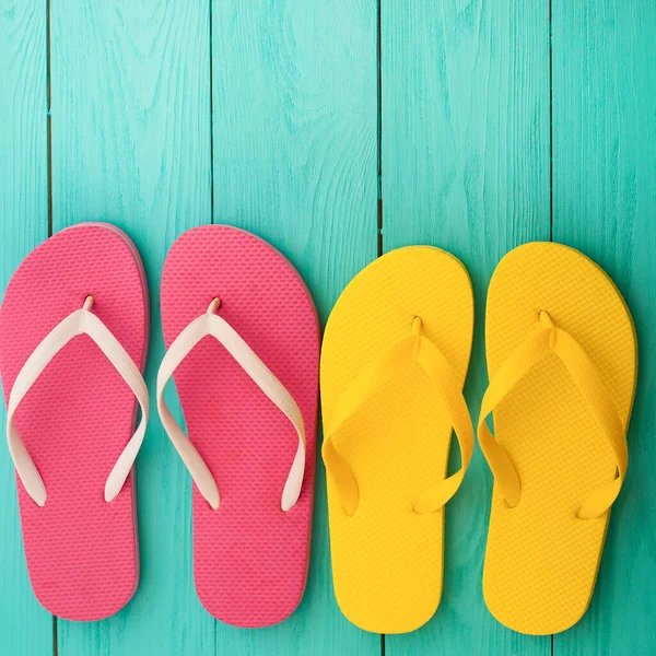 pink and yellow flip flops on blue wooden background top view free space