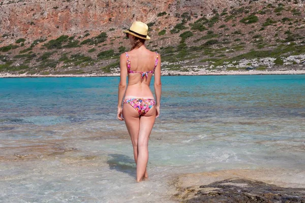 山や海を背景にビーチに立つ水着姿の女性の後ろ姿 — ストック写真