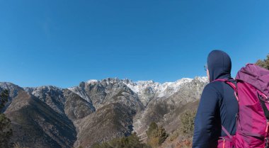 Mountaineer looking at the Sierra de Gredos with snow, view from the south side, travel ads and postcards, unusual views of the area clipart