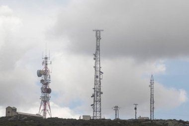 Dramatik bulutlu gökyüzünün altındaki bir dağ sırtındaki telekom kuleleri