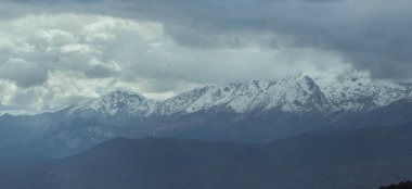 Arkasında dramatik bir gökyüzü olan karla kaplı Sierra 'nın panoramik fotoğrafı