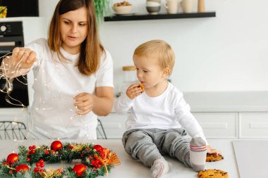 Güzel anne, sevimli oğluyla mutfakta oynuyor. Çiçek ailesi Noel için hazırlanıyor..