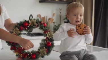 Anaokulundan bir çocuk Noel kurabiyesi yiyor. Mutlu aile, annem yeni yıl kutlamalarına hazırlanıyor.