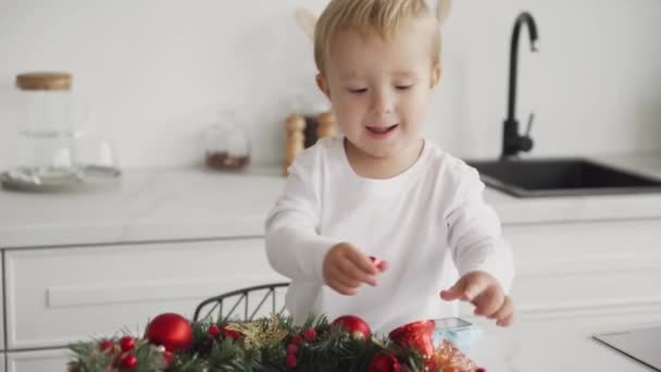 Przygotowuję Się Świąt Mały Chłopiec Uśmiecha Się Dekoruje Świąteczny Wieniec — Wideo stockowe