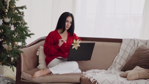 若い女性はクリスマスに一人ですが 彼女はインターネット上で彼女の家族に連絡するために彼女のラップトップコンピュータを使用しています — ストック動画