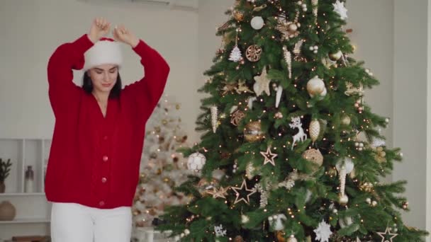 Νεαρή Γυναίκα Χορεύει Δίπλα Ένα Στολισμένο Χριστουγεννιάτικο Δέντρο Χαρούμενο Χαμογελαστό — Αρχείο Βίντεο