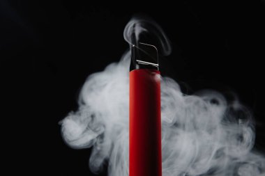 Siyah arka planda tek kullanımlık renkli bir e-sigara. Modern sigara, buhar ve nikotin kavramı. Sigara içmenin alternatifi, güvenli sigaralar. Sigarayı nasıl bırakacağımı.