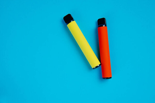 Two disposable e-cigarettes on a dark background. Electronic vape, an alternative to smoking cigarettes