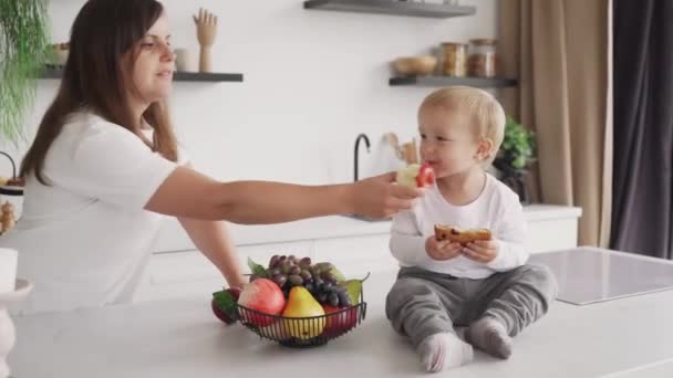 ママは子供に健康的な食べ物を食べさせようとしますが 子供は手を押し出してクッキーを食べ続けます — ストック動画