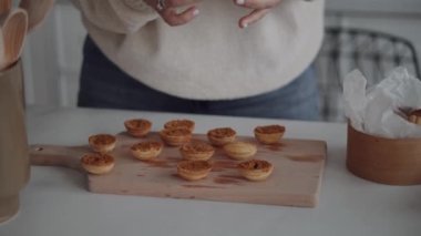 Pasta şefi renkli arka planda haşlanmış sütle ceviz şeklinde kurabiyeler pişiriyor. Ev hanımı tatlı pişiriyor, ev işi yapıyor, mesleğini yapıyor..