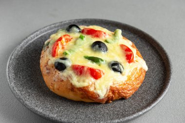 Peynirli, zeytinli, domatesli ve yeşil biberli ev yapımı pizza. Gri arkaplandaki üst görünüm. Mini pizza.