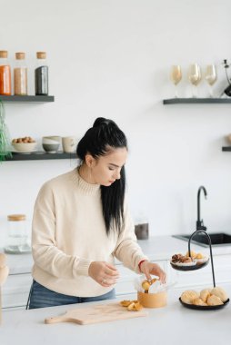 Pasta şefi renkli arka planda haşlanmış sütle ceviz şeklinde kurabiyeler pişiriyor. Ev hanımı tatlı pişiriyor, ev işi yapıyor, mesleğini yapıyor..