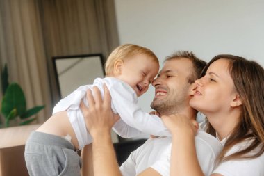 Gülümseyen bir baba kucağında bir bebek taşıyor annesi yanında. Mutlu Aile Yaşam Stili. Bebek gülümsüyor ve gülüyor. Mutlu bir çocukluk ve sağlıklı bir aile, mutlu aile ilişkileri..