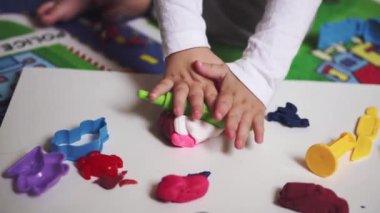 Plastikle oynayan bir çocuğun elleri, üst görünüm..