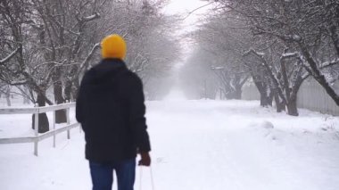 Bir çocukla parkta kış yürüyüşü. Baba kışın çocuğuyla parkta yürür. Baba oğlunu kızakla gezdiriyor..