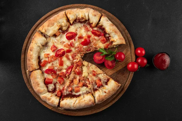 Cooked pizza with ingredients next to make tomato sauce, mozzarella, tomatoes, olive oil, cheese, spices, served on a rustic wooden table. Flat form. Italian margarita pizza