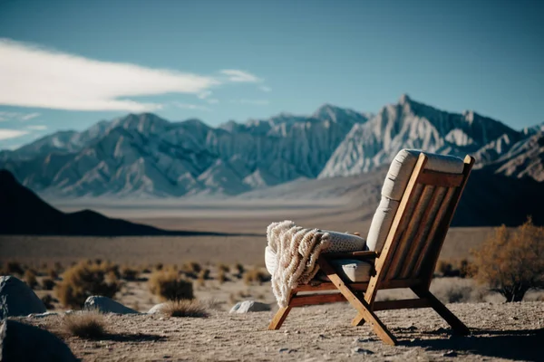 An armchair with a plaid against a backdrop of mountains. A space for solitude, slowing down and relaxation. Balance with the environment. Nature retreat in the mountains.