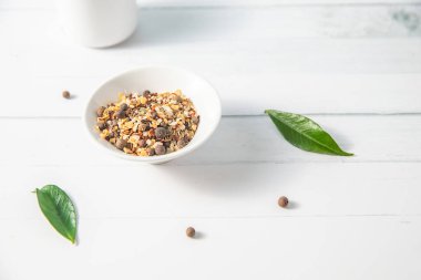 Beyaz ahşap arka planda küçük bir kasede çeşitli baharatlar diğer beyaz mutfak eşyaları ve yeşil yapraklarla birlikte. Yüksek kalite fotoğraf