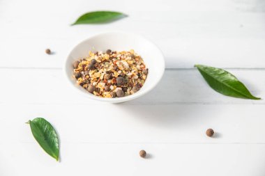 Beyaz ahşap arka planda küçük bir kasede çeşitli baharatlar diğer beyaz mutfak eşyaları ve yeşil yapraklarla birlikte. Yüksek kalite fotoğraf