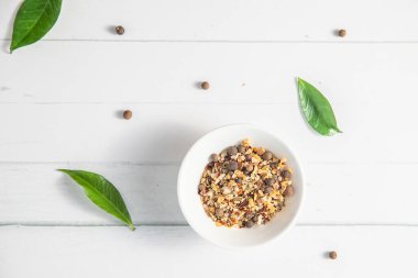 Beyaz ahşap arka planda küçük bir kasede çeşitli baharatlar diğer beyaz mutfak eşyaları ve yeşil yapraklarla birlikte. Yüksek kalite fotoğraf