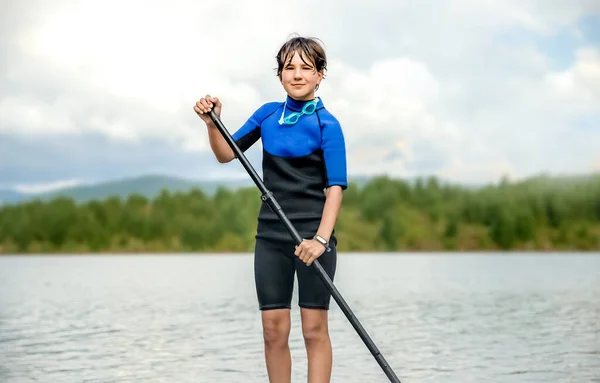 Active Teen Girl Paddling Sup Board River Lake Natural Background 图库图片